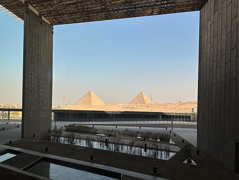 Una escalera de seis pisos bordeada de estatuas antiguas conduce a las galerías principales y a una vista de las pirámides. El Cairo, Egipto. 14 de junio de 2025. Evelyn Dom